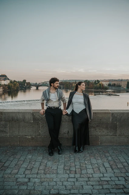 Prague couple photoshoot: couple holding hands at the bridge parapet. Couple holding hands at the bridge parapet during a couple photoshoot in Prague.
