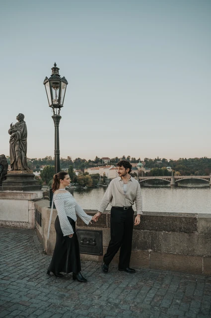 Prague couple photoshoot: couple holding hands beneath the bridge lamp. Couple holding hands beneath the bridge lamp during a couple photoshoot in Prague.