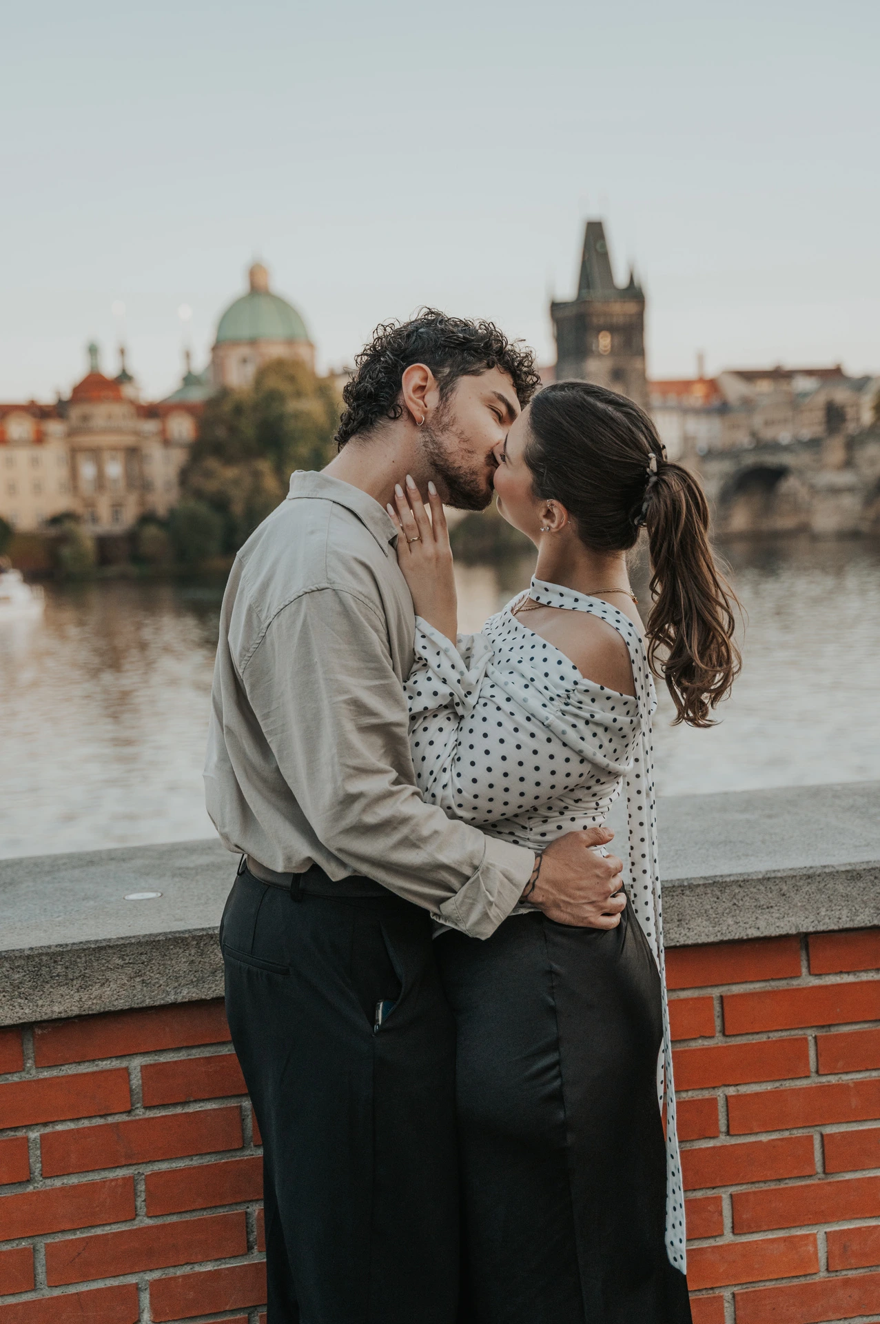 Couple kissing with Charles Bridge in the background during a couple photoshoot in Prague.
