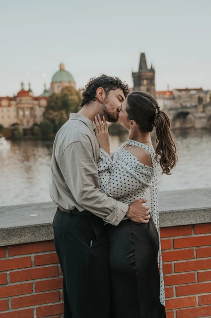 Prague couple photoshoot: couple kissing with Charles Bridge in the background. Couple kissing with Charles Bridge in the background during a couple photoshoot in Prague.