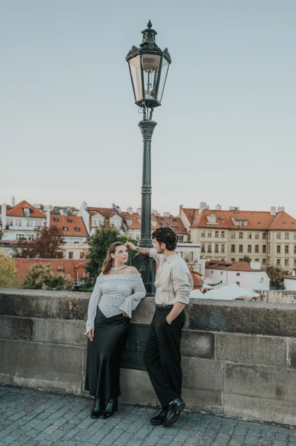 Prague couple photoshoot: couple laughing beside the bridge parapet. Couple laughing beside the bridge parapet during a couple photoshoot in Prague.