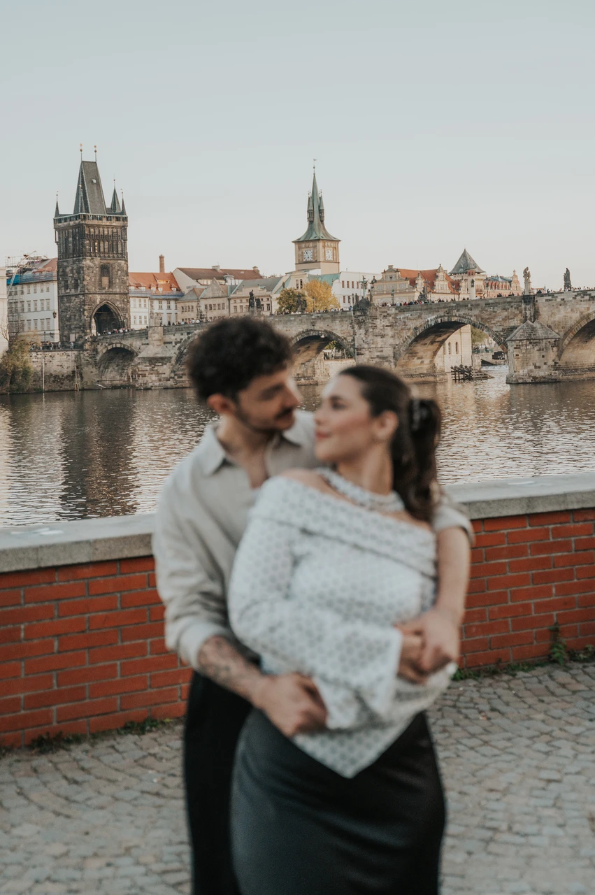 Prague couple photoshoot: couple laughing together in a close riverside embrace. Couple laughing together in a close riverside embrace during a couple photoshoot in Prague.