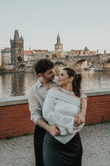 Couple laughing together in a close riverside embrace during a couple photoshoot in Prague.