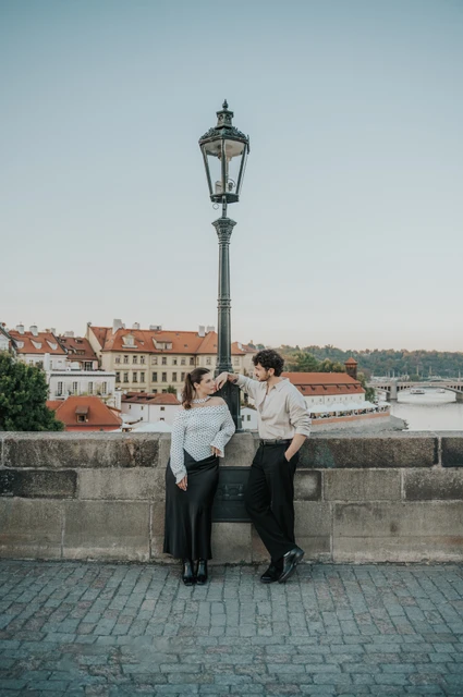Prague couple photoshoot: couple leaning together beneath a Charles Bridge lamp. Couple leaning together beneath a Charles Bridge lamp during a couple photoshoot in Prague.