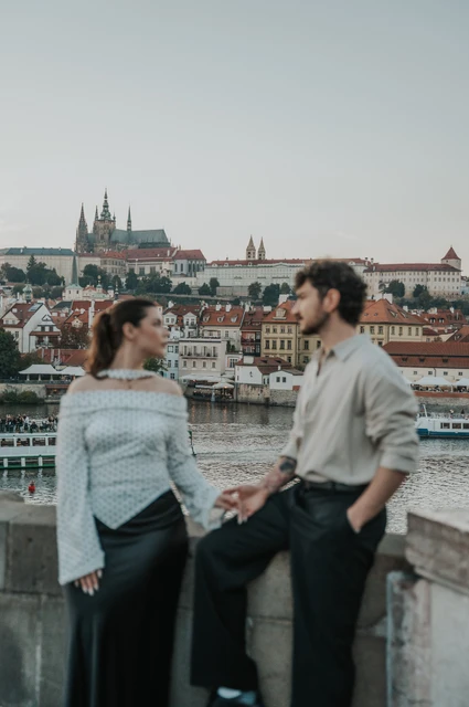 Prague couple photoshoot: couple looking at each other over the river. Couple looking at each other over the river during a couple photoshoot in Prague.