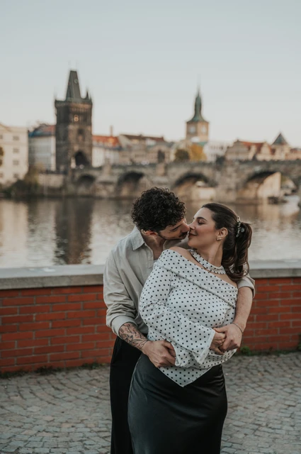 Prague couple photoshoot: couple sharing a kiss beside the riverside wall. Couple sharing a kiss beside the riverside wall during a couple photoshoot in Prague.