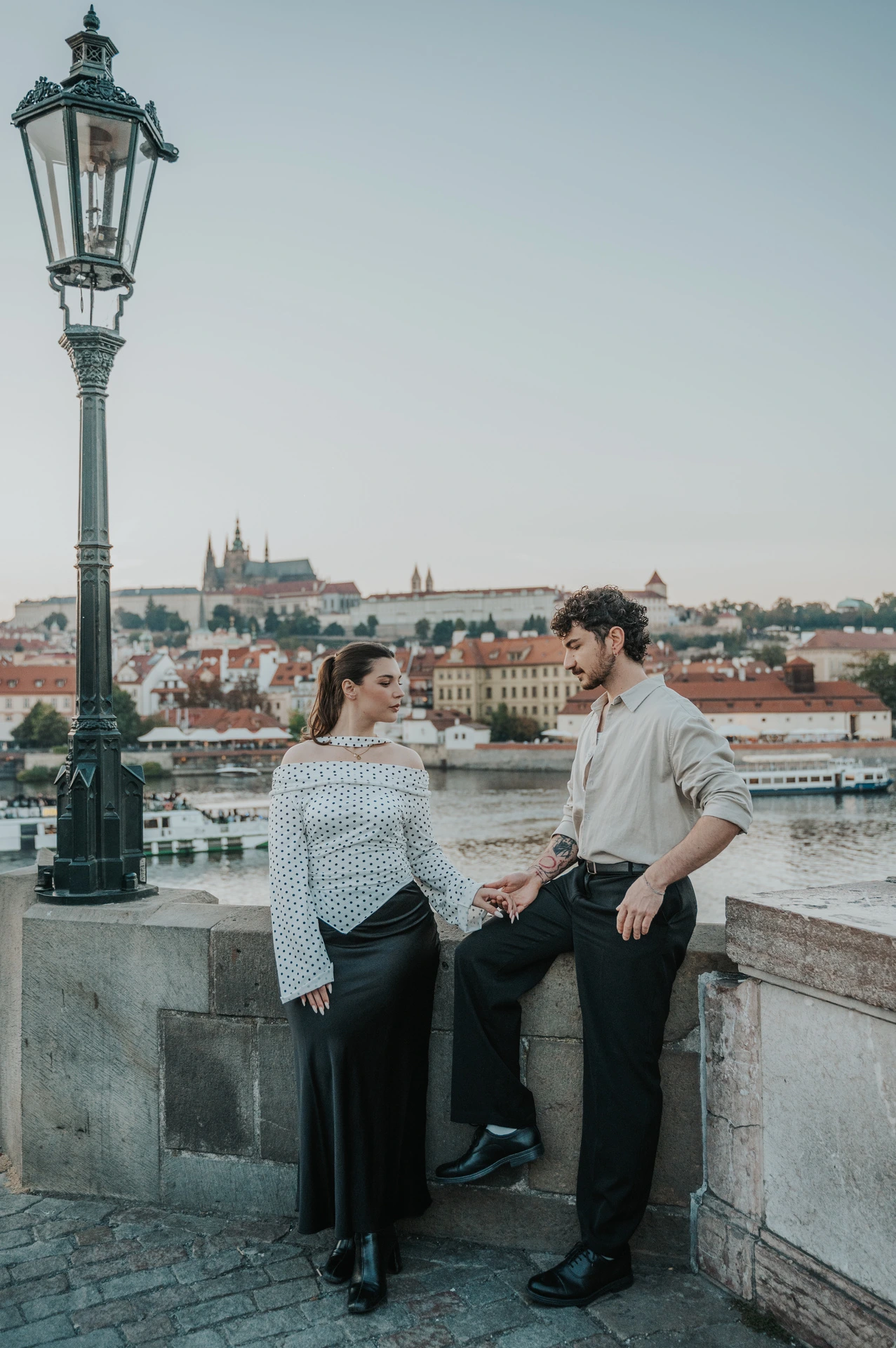 Couple sharing a smile by the Charles Bridge wall during a couple photoshoot in Prague.