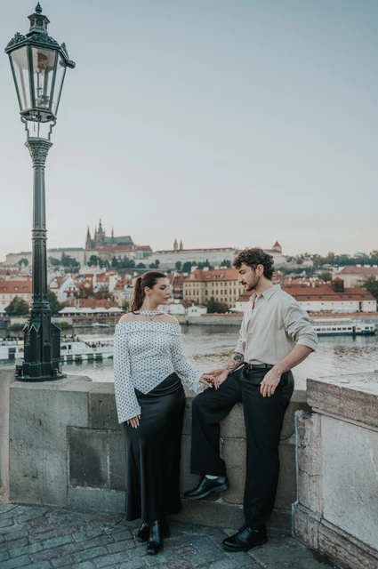 Prague couple photoshoot: couple sharing a smile by the Charles Bridge wall. Couple sharing a smile by the Charles Bridge wall during a couple photoshoot in Prague.
