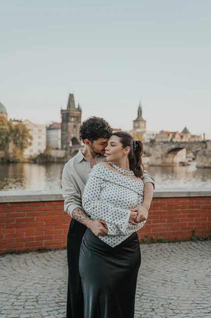 Prague couple photoshoot: couple smiling as they hold each other by the brick wall. Couple smiling as they hold each other by the brick wall during a couple photoshoot in Prague.