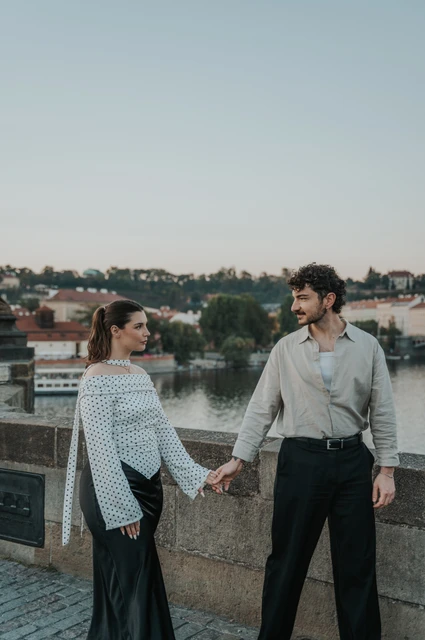 Prague couple photoshoot: couple smiling at one another on Charles Bridge. Couple smiling at one another on Charles Bridge during a couple photoshoot in Prague.