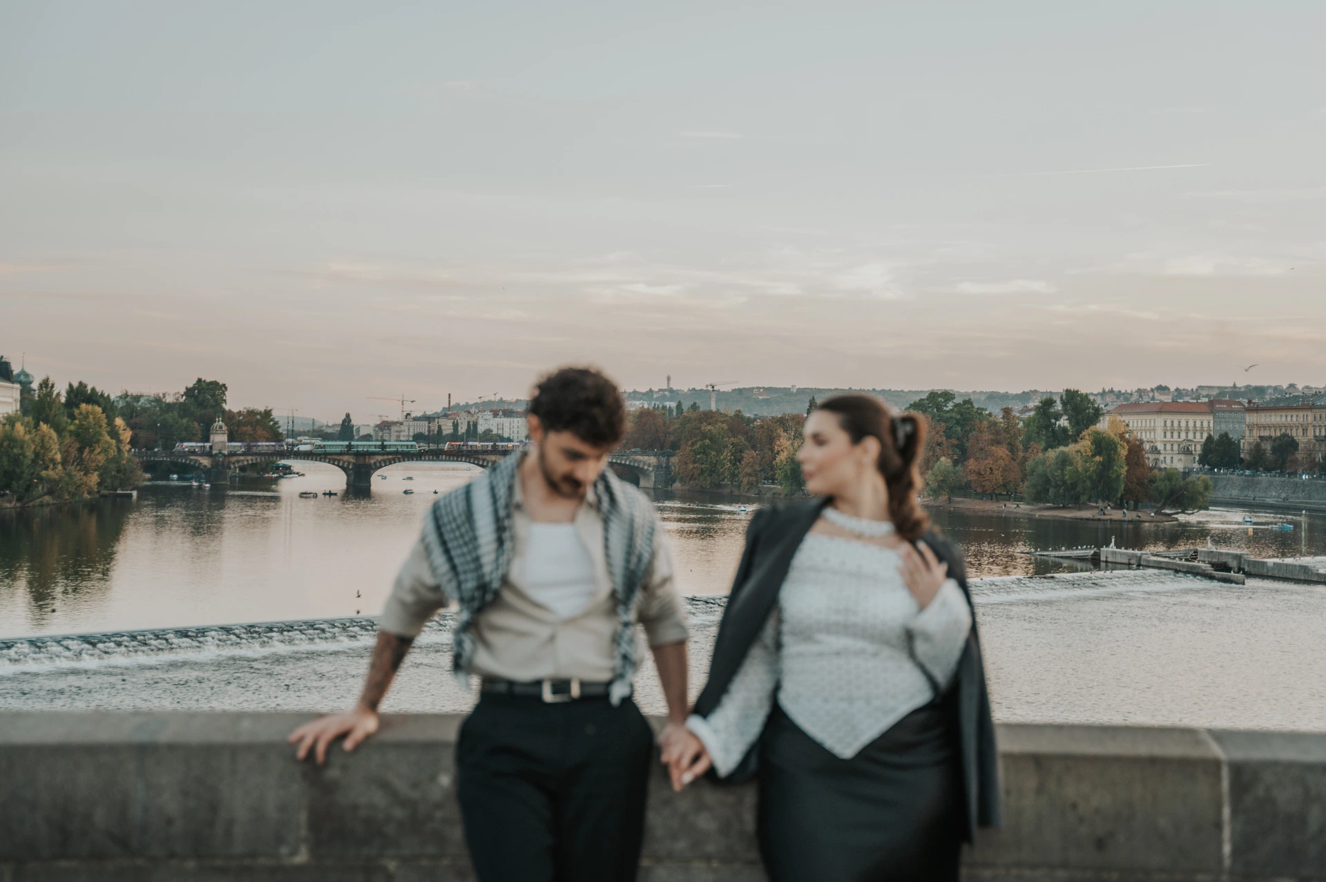 Couple smiling beside the river with a checked wrap during a couple photoshoot in Prague.