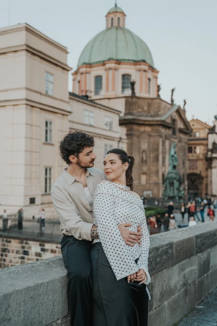 Prague couple photoshoot: couple smiling in a close embrace on the bridge. Couple smiling in a close embrace on the bridge during a couple photoshoot in Prague.