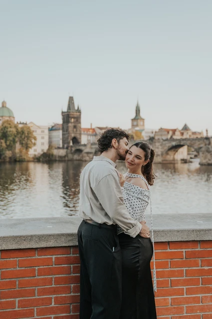 Prague couple photoshoot: couple smiling together against the river view. Couple smiling together against the river view during a couple photoshoot in Prague.