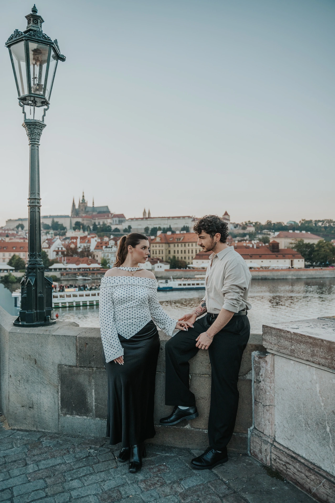 Couple smiling with the river rooftops behind them during a couple photoshoot in Prague.