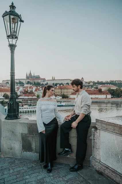 Prague couple photoshoot: couple smiling with the river rooftops behind them. Couple smiling with the river rooftops behind them during a couple photoshoot in Prague.