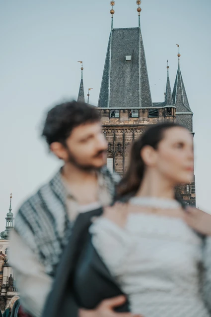 Prague couple photoshoot: soft-focus portrait of the couple by the bridge tower. Soft-focus portrait of the couple by the bridge tower during a couple photoshoot in Prague.