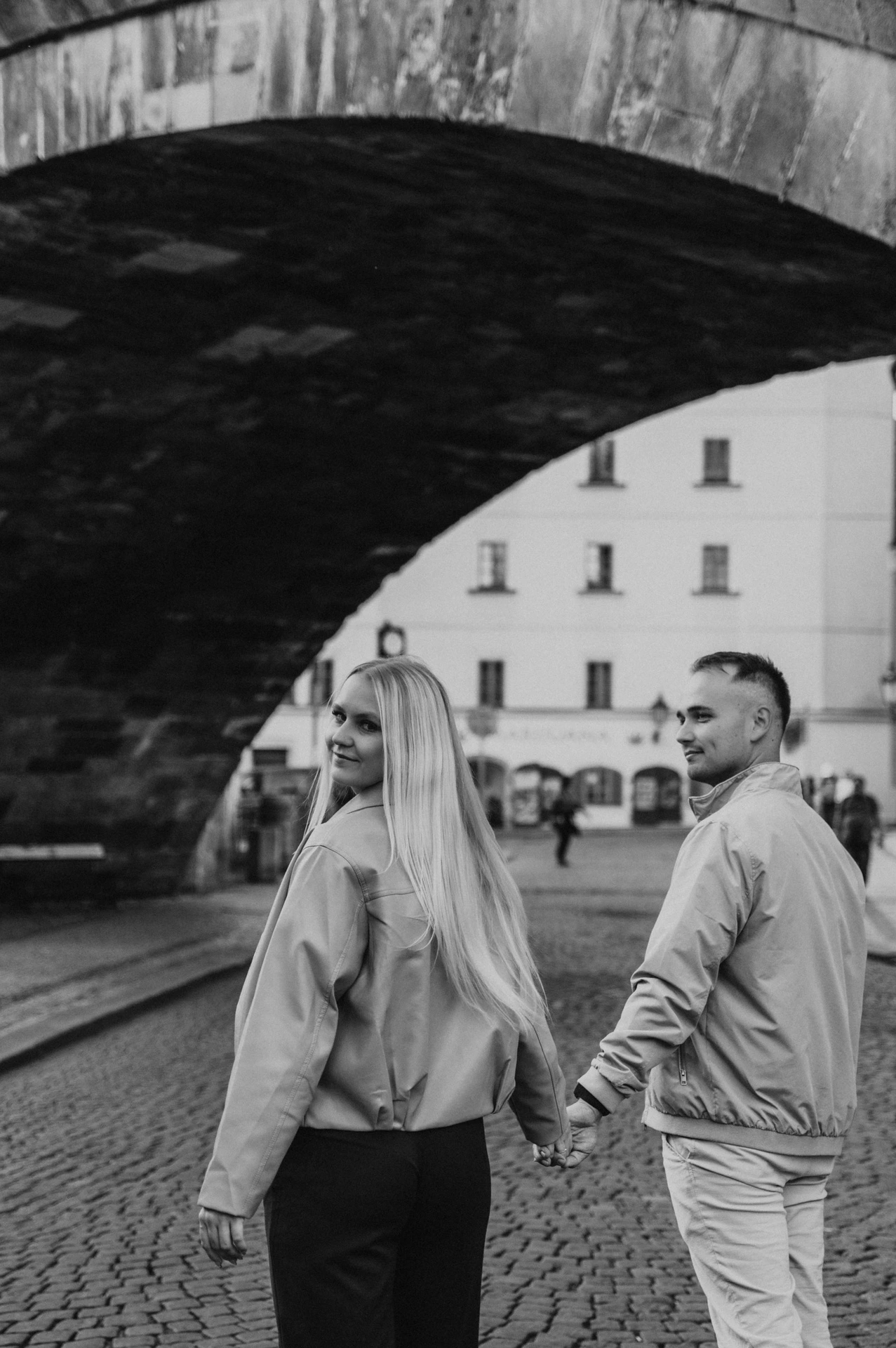 Black and white portrait below the Charles Bridge arch during a couple photoshoot in Prague.