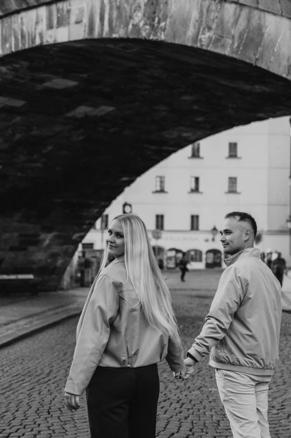 Prague couple photoshoot: black and white portrait below the Charles Bridge arch. Black and white portrait below the Charles Bridge arch during a couple photoshoot in Prague.