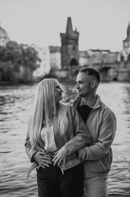 Prague couple photoshoot: black and white portrait of the couple laughing by the river. Black and white portrait of the couple laughing by the river during a couple photoshoot in Prague.