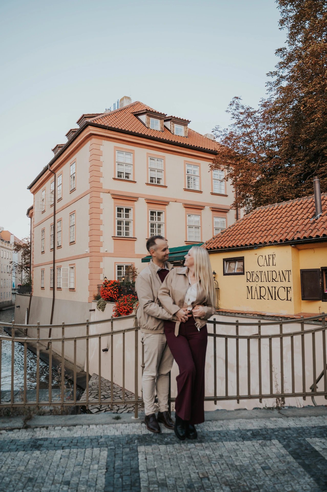 Couple embracing beside the Kampa canal railings during a couple photoshoot in Prague.