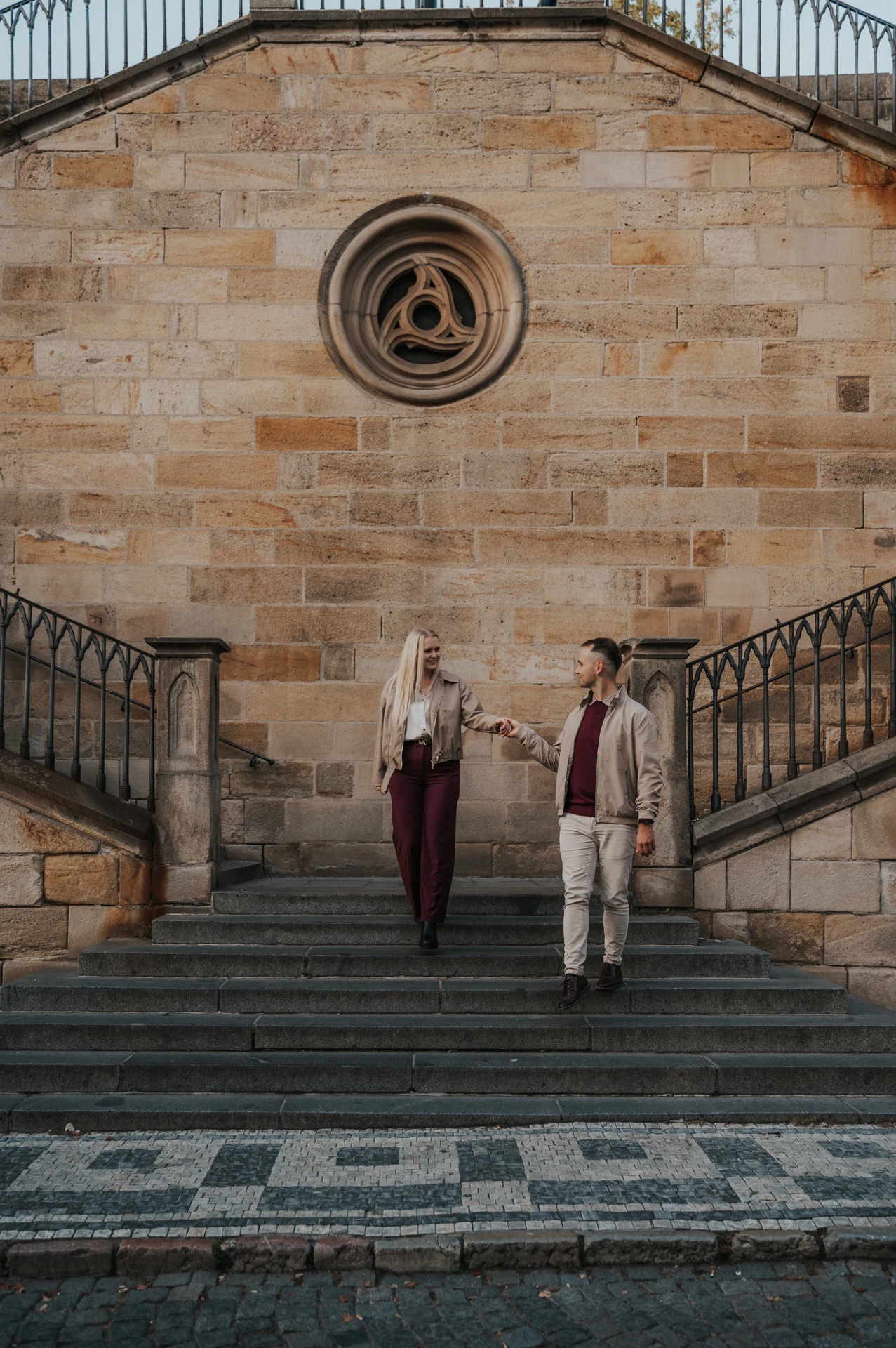 Couple holding hands on the broad stone staircase during a couple photoshoot in Prague.
