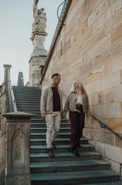 Prague couple photoshoot: couple holding hands on the narrow stone stairs. Couple holding hands on the narrow stone stairs during a couple photoshoot in Prague.