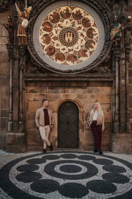 Prague couple photoshoot: couple holding hands under the decorated clock face. Couple holding hands under the decorated clock face during a couple photoshoot in Prague.