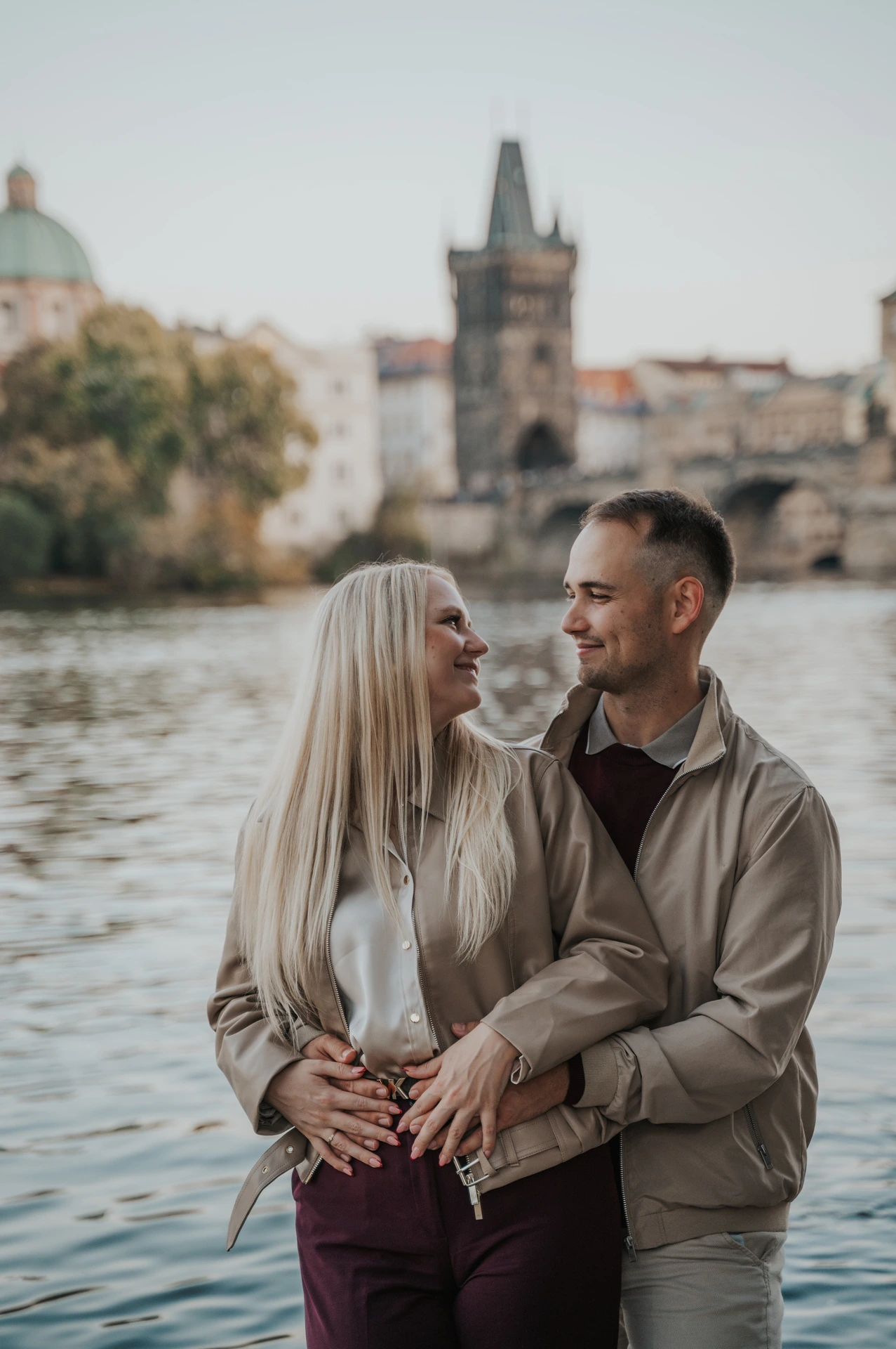 Couple laughing together beside the Vltava during a couple photoshoot in Prague.