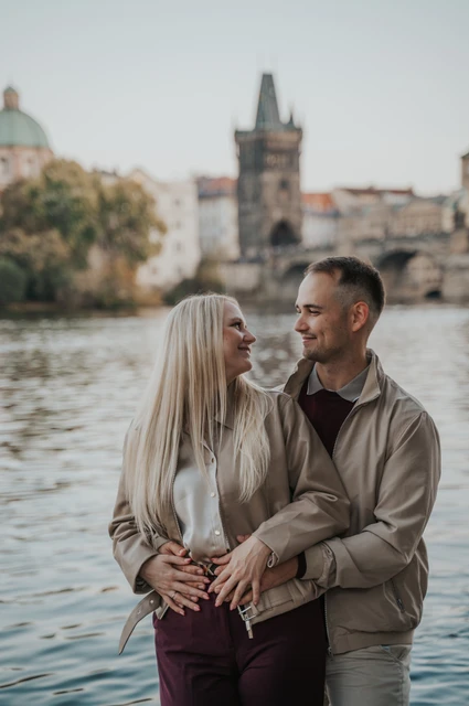 Prague couple photoshoot: couple laughing together beside the Vltava. Couple laughing together beside the Vltava during a couple photoshoot in Prague.