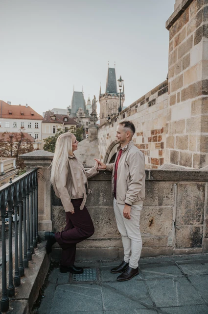 Prague couple photoshoot: couple leaning against the wall at the top of the bridge stairs. Couple leaning against the wall at the top of the bridge stairs during a couple photoshoot in Prague.