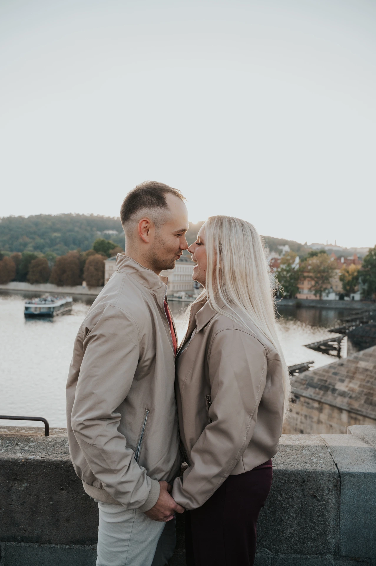 Couple leaning in for a kiss beside the bridge parapet during a couple photoshoot in Prague.
