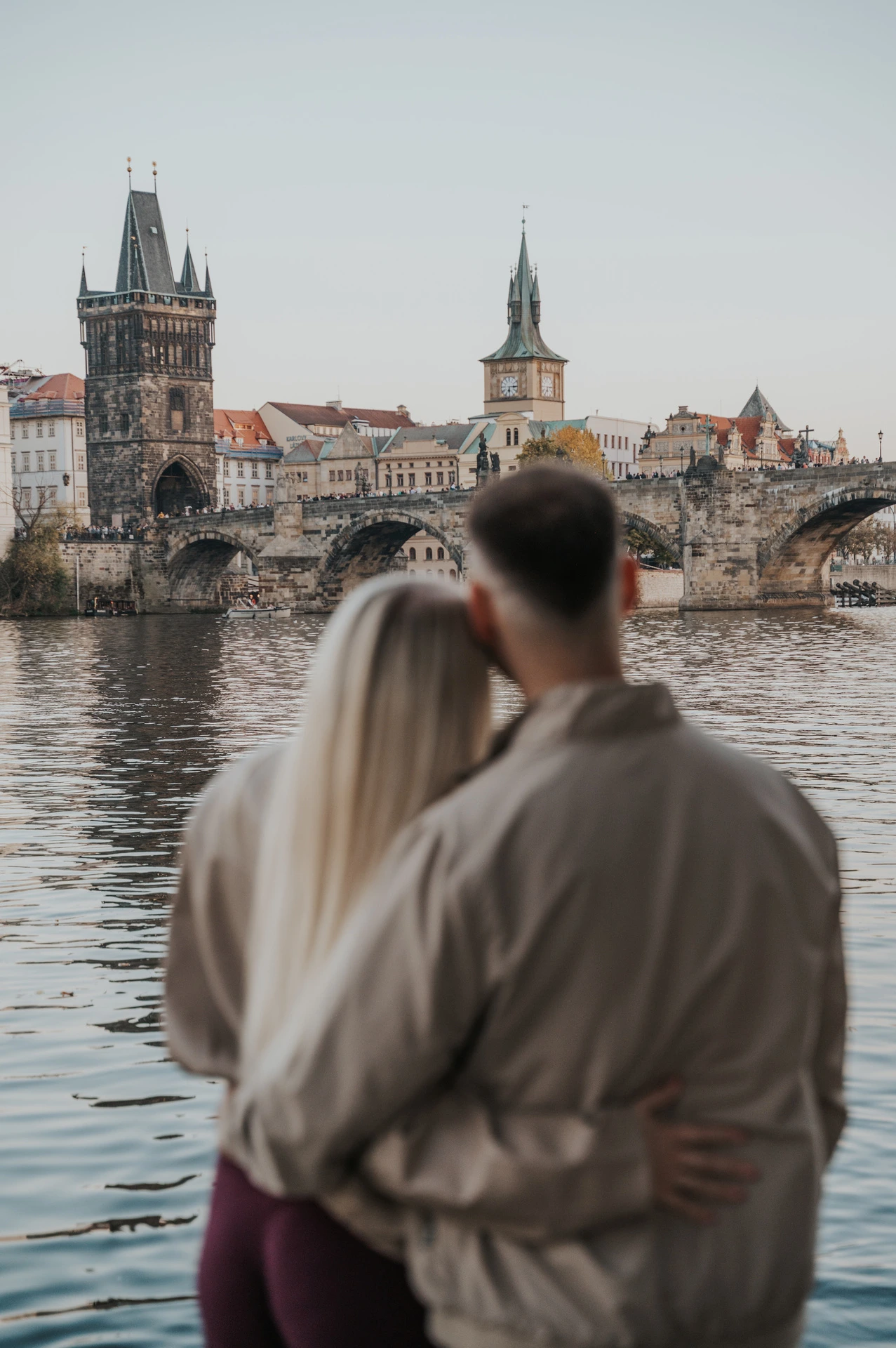Couple looking across the water towards Charles Bridge during a couple photoshoot in Prague.
