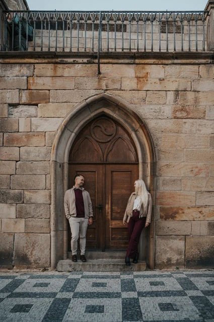 Prague couple photoshoot: couple pausing either side of an arched wooden door. Couple pausing either side of an arched wooden door during a couple photoshoot in Prague.