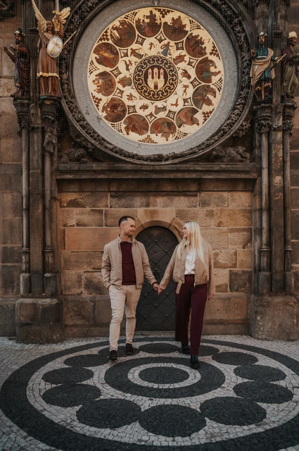 Prague couple photoshoot: couple reaching towards each other at the Astronomical Clock. Couple reaching towards each other at the Astronomical Clock during a couple photoshoot in Prague.