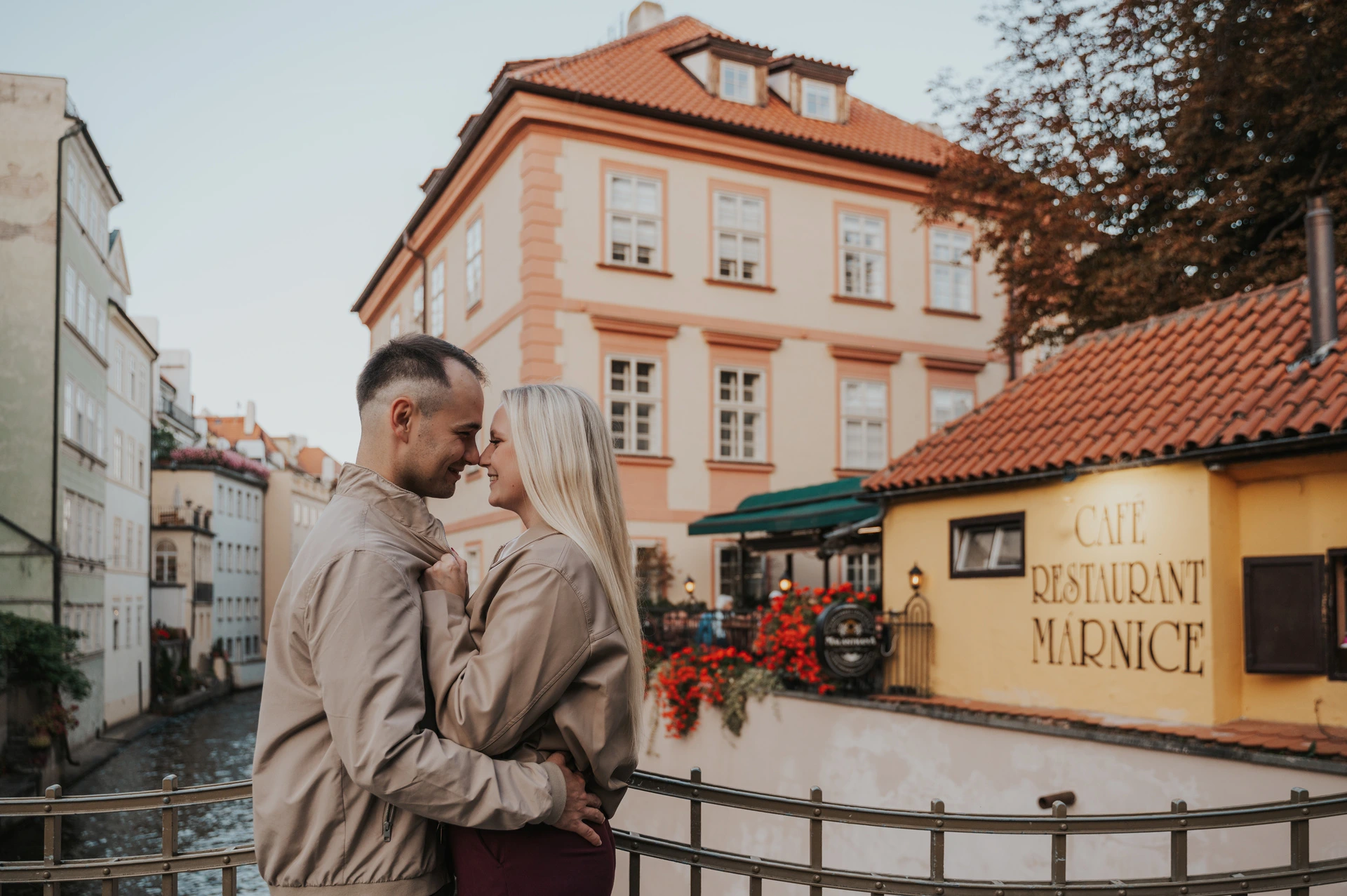 Couple sharing a kiss with colourful Kampa houses behind them during a couple photoshoot in Prague.
