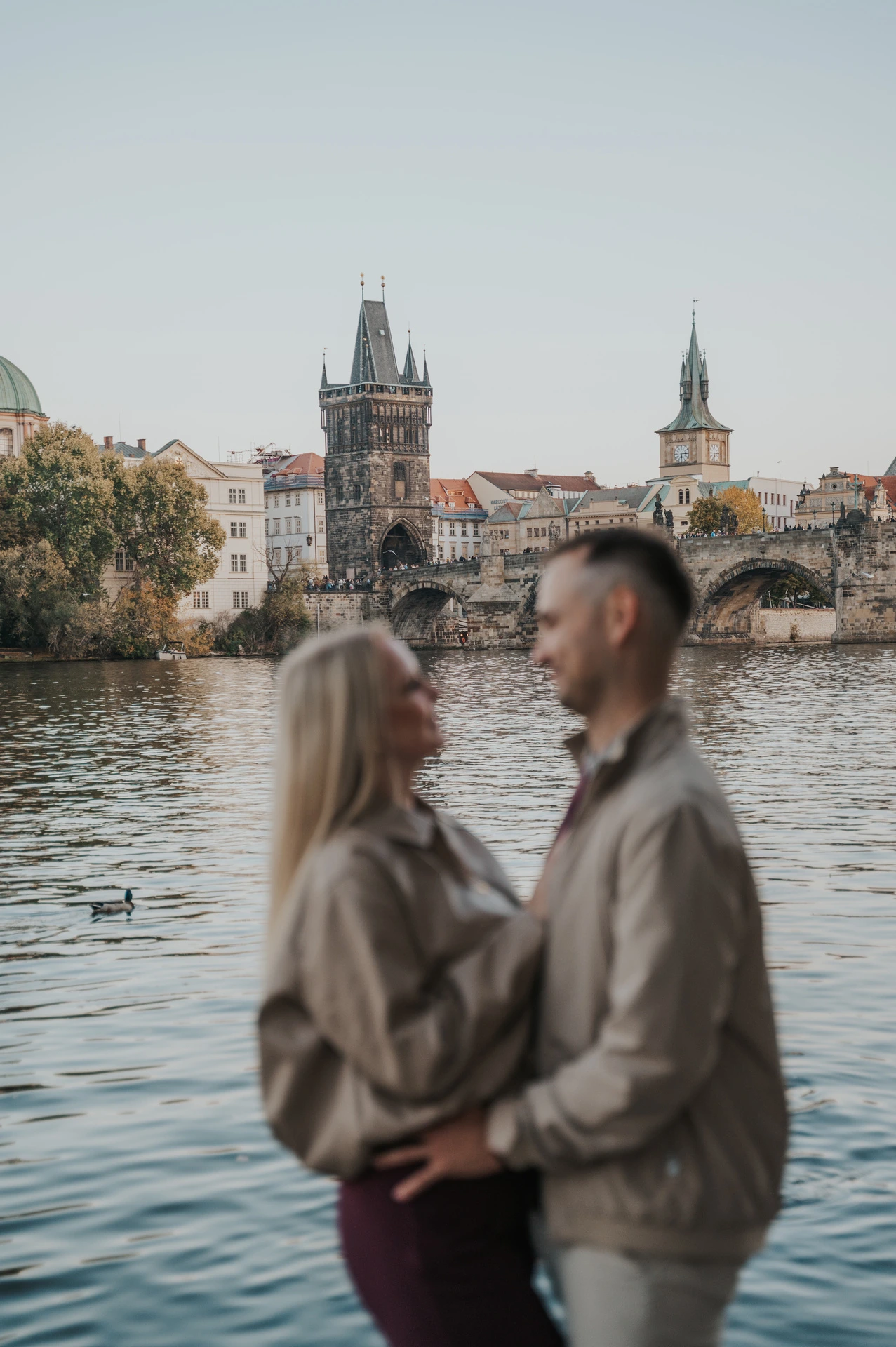 Couple smiling together with Charles Bridge in the background during a couple photoshoot in Prague.