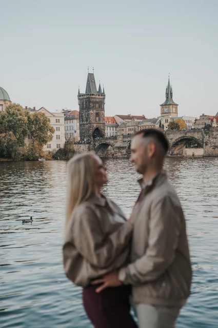 Prague couple photoshoot: couple smiling together with Charles Bridge in the background. Couple smiling together with Charles Bridge in the background during a couple photoshoot in Prague.