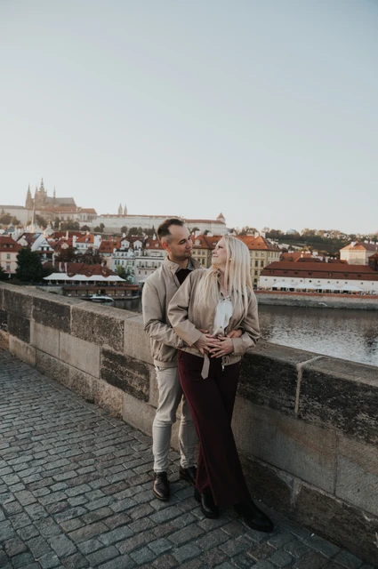 Prague couple photoshoot: couple standing close against the bridge wall. Couple standing close against the bridge wall during a couple photoshoot in Prague.