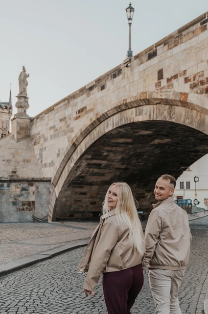 Prague couple photoshoot: couple turning towards the camera beside a bridge arch. Couple turning towards the camera beside a bridge arch during a couple photoshoot in Prague.
