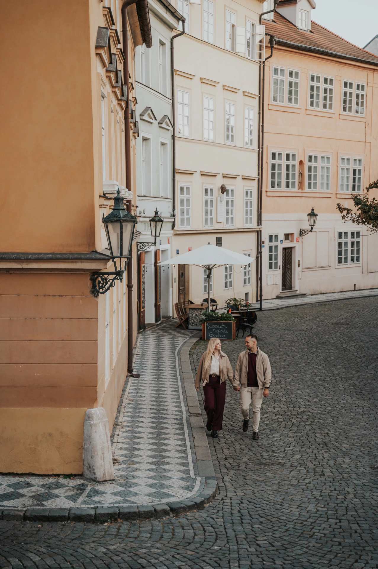 Couple walking into a cobbled Kampa street during a couple photoshoot in Prague.