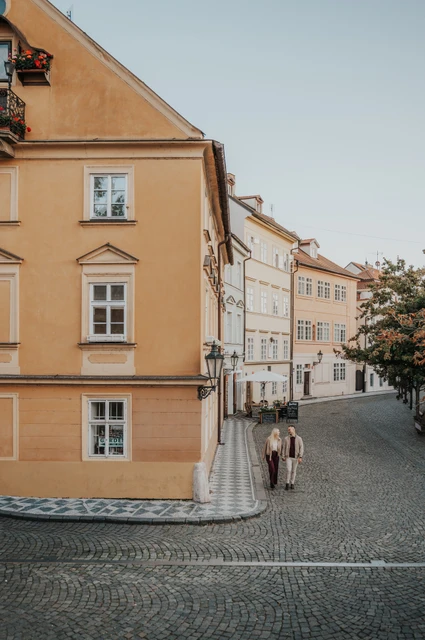 Prague couple photoshoot: wide view of the couple beside a yellow Kampa building. Wide view of the couple beside a yellow Kampa building during a couple photoshoot in Prague.