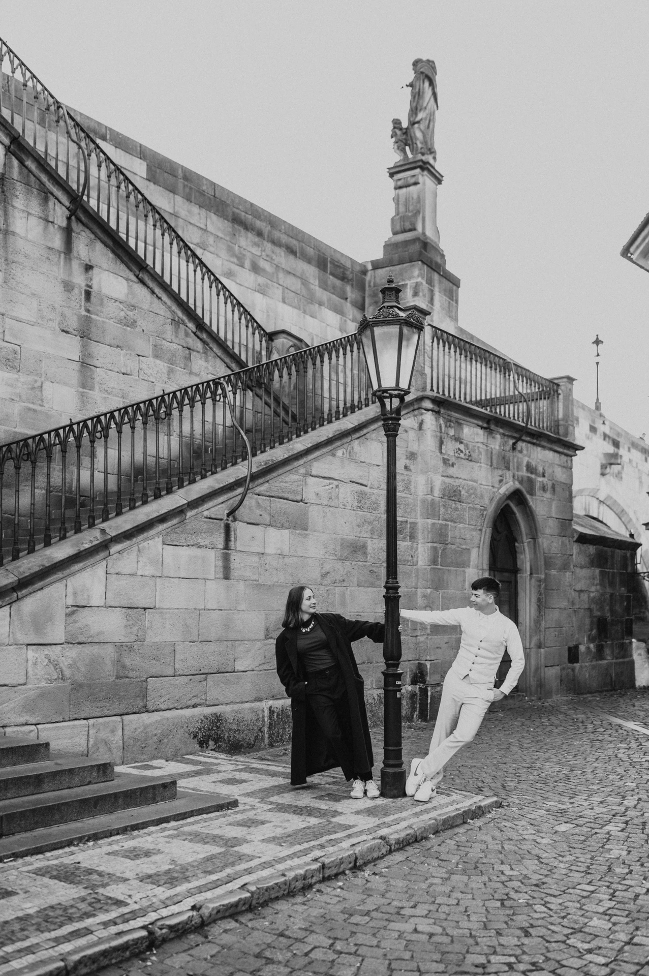 Black and white portrait beside the Charles Bridge stairway during a couple photoshoot in Prague.