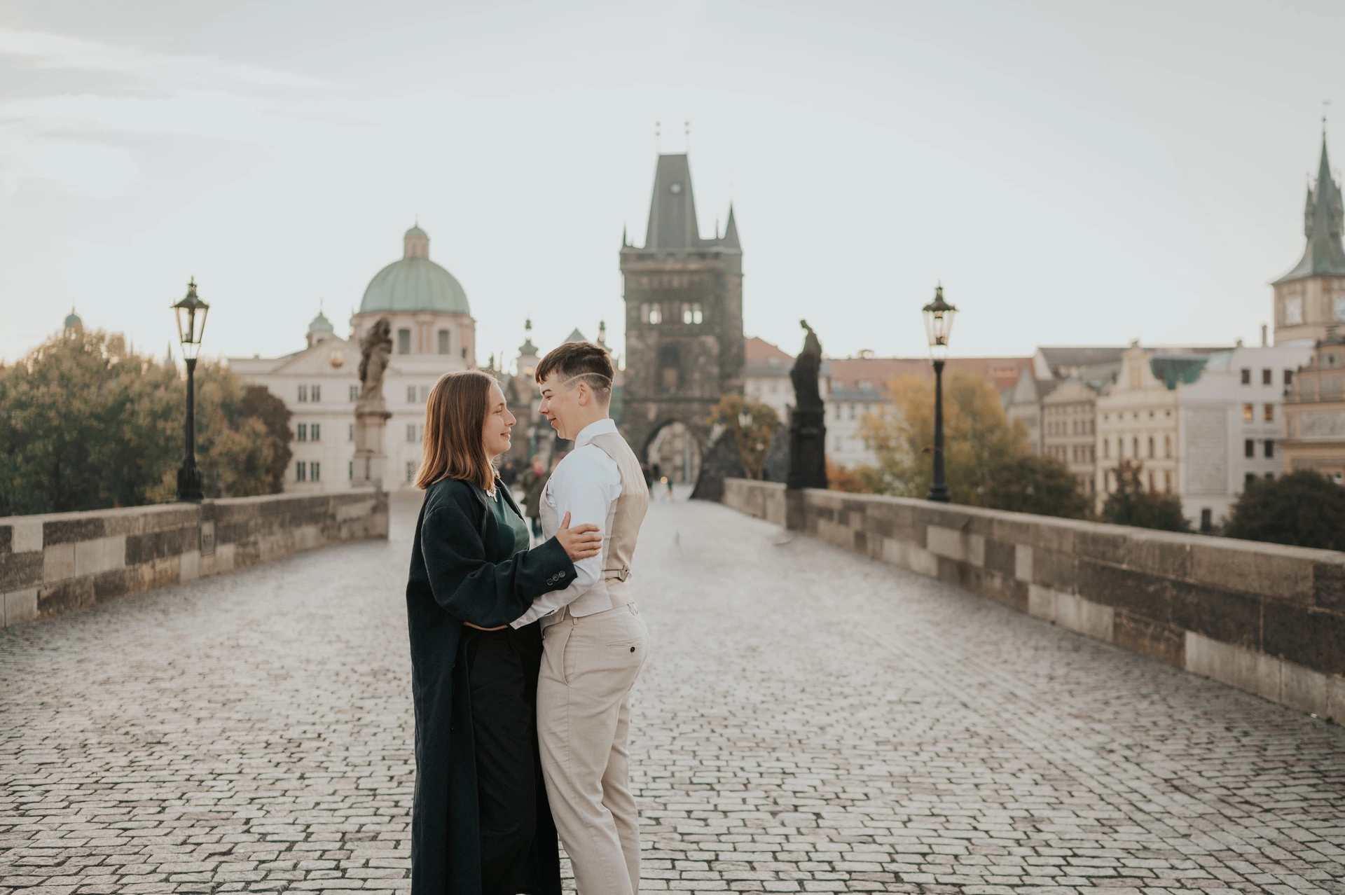 Prague couple photoshoot: couple embracing between the Charles Bridge parapets. Couple embracing between the Charles Bridge parapets during a couple photoshoot in Prague.