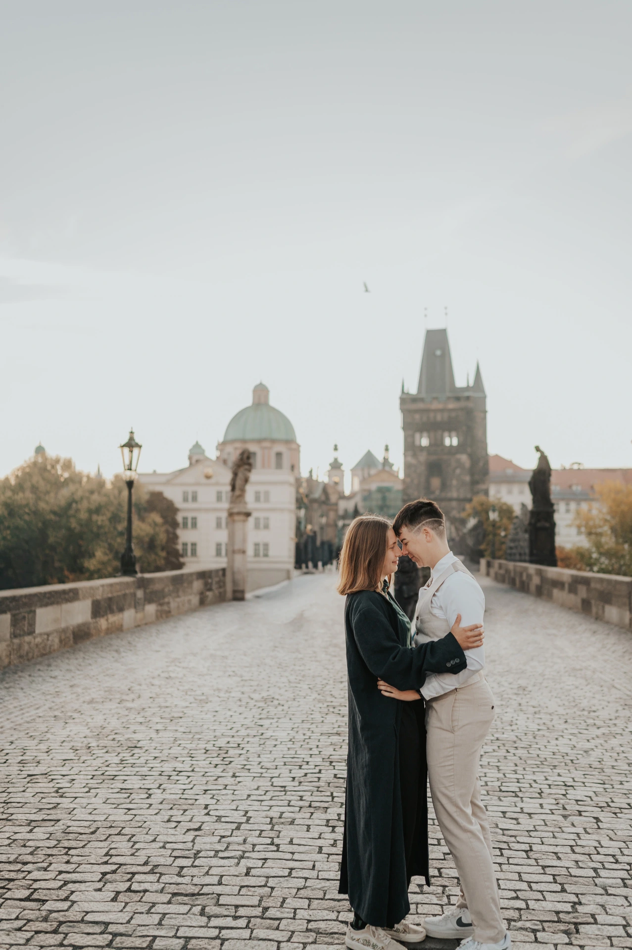 Couple kissing on the cobblestones of Charles Bridge during a couple photoshoot in Prague.
