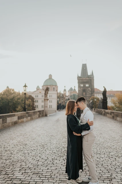 Couple kissing on the cobblestones of Charles Bridge during a couple photoshoot in Prague.