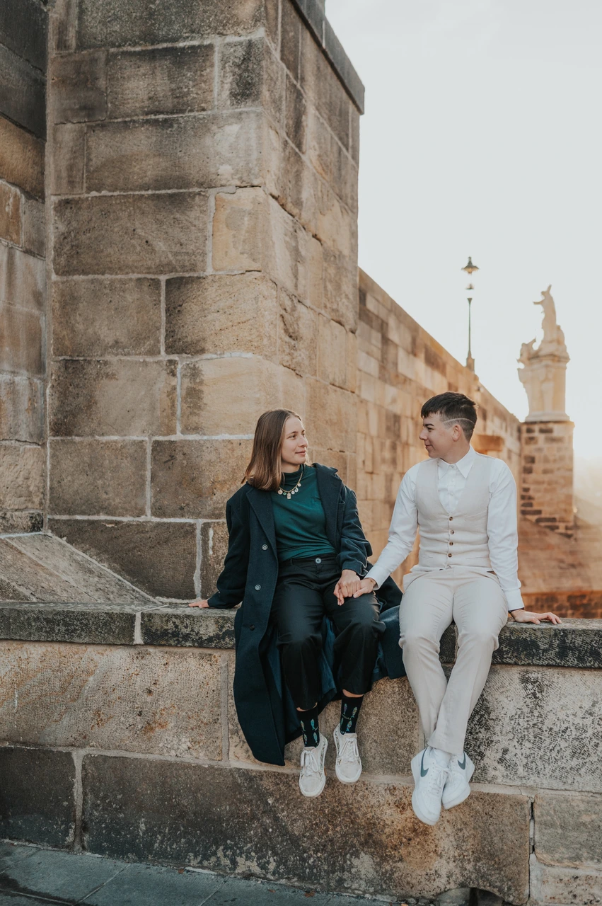 Prague couple photoshoot: couple leaning towards each other on the stone ledge. Couple leaning towards each other on the stone ledge during a couple photoshoot in Prague.