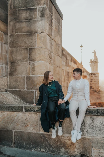 Prague couple photoshoot: couple leaning towards each other on the stone ledge. Couple leaning towards each other on the stone ledge during a couple photoshoot in Prague.