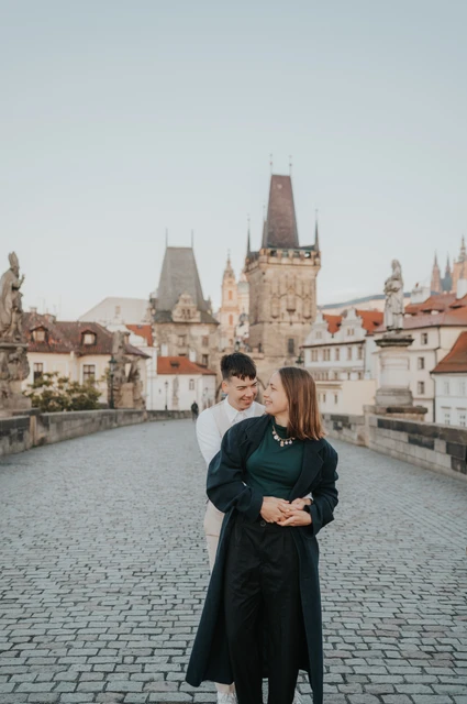 Prague couple photoshoot: couple looking at each other beneath the bridge towers. Couple looking at each other beneath the bridge towers during a couple photoshoot in Prague.