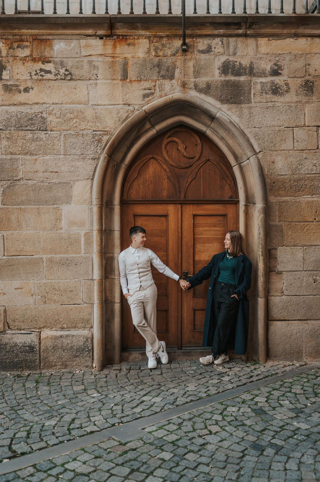 Couple reaching for each other beside the wooden doorway during a couple photoshoot in Prague.