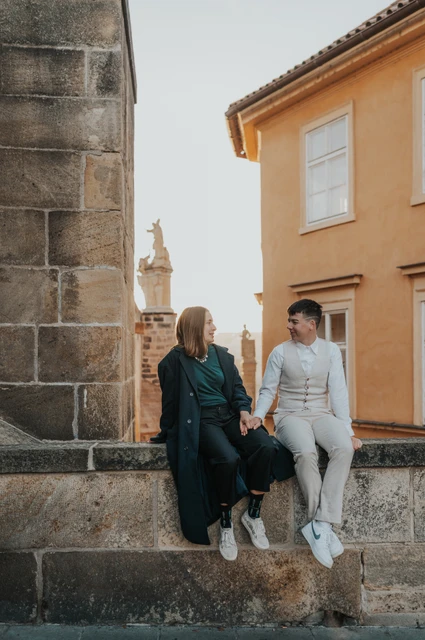 Couple seated together on a stone ledge in Kampa during a couple photoshoot in Prague.
